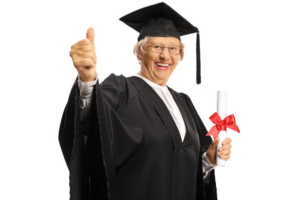 Mulher idosa em um vestido de formatura segurando um diploma e mostrando — Fotografia de Stock