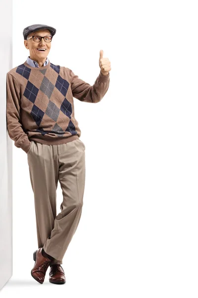 Starší pán opřený o zeď a ukazující palce nahoru — Stock fotografie