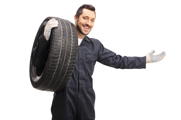 Auto mechanic with a tire gesturing welcome with hand 
