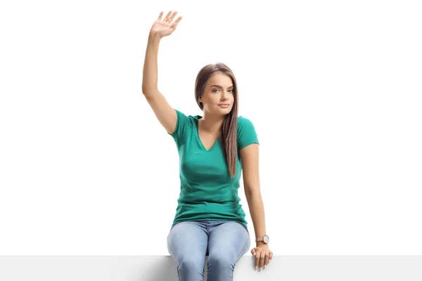 Beautiful young female sitting on a blank board and waving — Stock Photo, Image