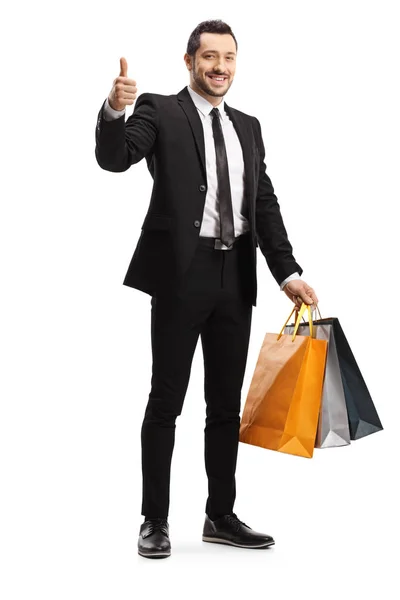 Młody biznesmen z torbami na zakupy z kciukiem w górze — Zdjęcie stockowe