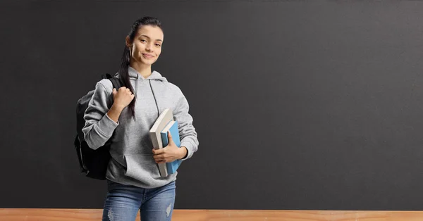 Kvinna student med böcker och ryggsäck står framför en bl — Stockfoto