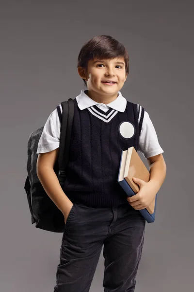 Niño en uniforme escolar sosteniendo libros y sonriendo —  Fotos de Stock