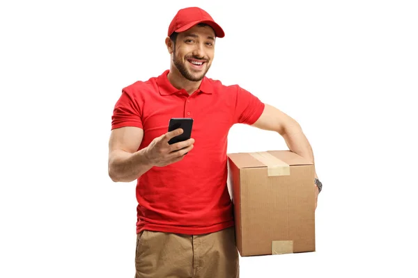 Delivery guy holding a box and a mobile phone and smiling at the — 스톡 사진