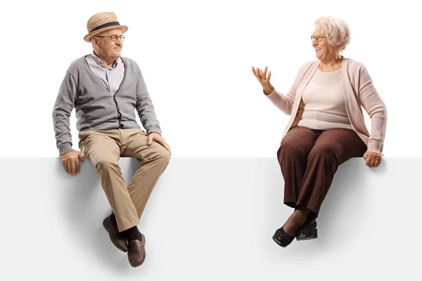 Homem e mulher idosos conversando e sentados em um painel em branco — Fotografia de Stock