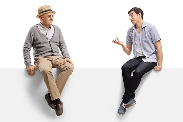 Ein älterer Mann und ein junger Mann reden und sitzen auf einer leeren Platte — Stockfoto