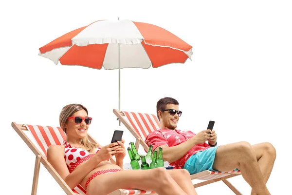 Young man and woman with phones sunbathing in deck chairs — 스톡 사진