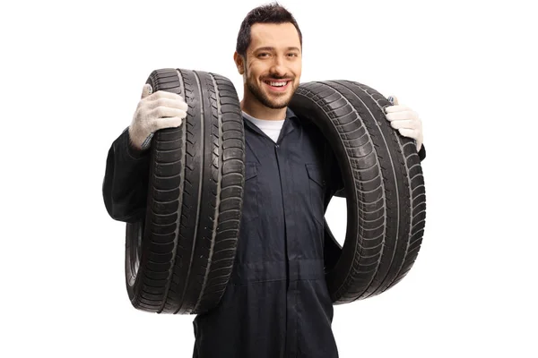 Un mécanicien automobile portant deux pneus de voiture — Photo