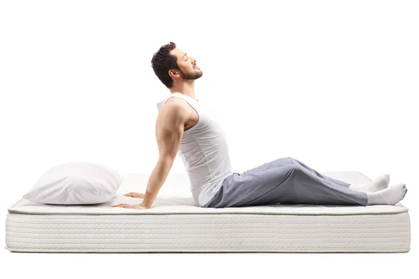 Young man in pajamas stretching in the morning on a mattress — 스톡 사진