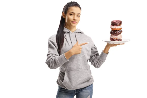 Jovem fêmea segurando um prato de donuts e apontando — Fotografia de Stock