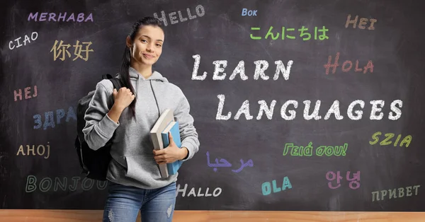 Female student standing in front of a blackboard with hello writ — Stock Photo, Image
