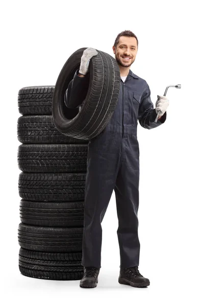 Mécanicien automobile en uniforme avec un pneu de voiture et une clé — Photo