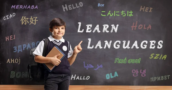 Schoolboy in a uniform pointing to a school board with hello in — Stock Photo, Image