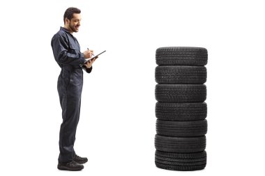 Formalı bir araba tamircisi bir belgeye pano ile yazı yazıyor.