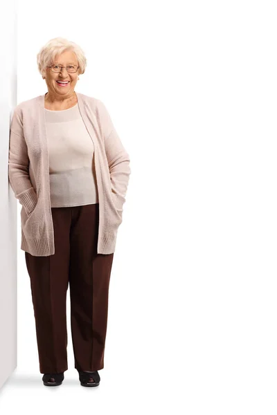 Ältere Frau posiert neben einer Mauer — Stockfoto