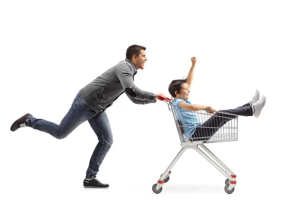 Baba oğlunu alışveriş arabasının içine itiyor. — Stok fotoğraf