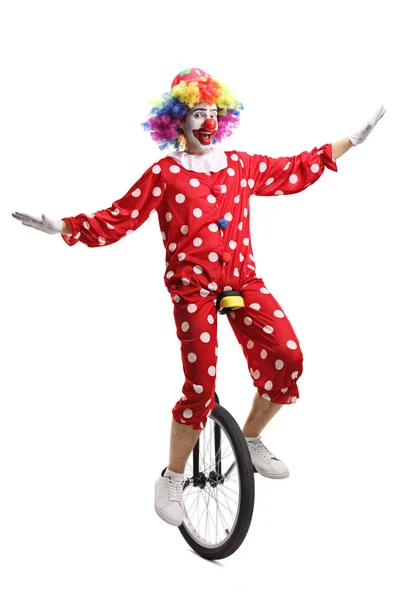 Клоун в красном костюме в горошек на одноколесном велосипеде — стоковое фото