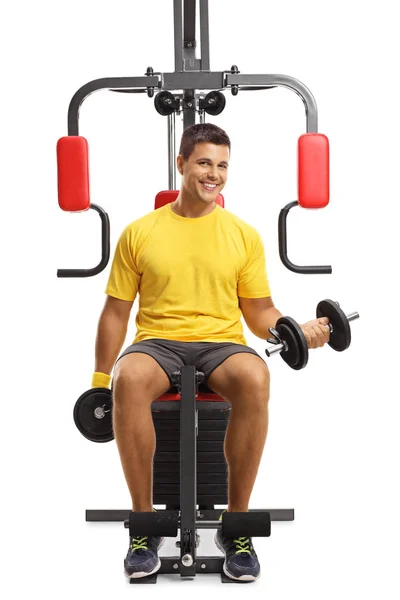 Młodzieniec trenujący z ciężarkami na urządzeniu fitness i uśmiechnięty — Zdjęcie stockowe