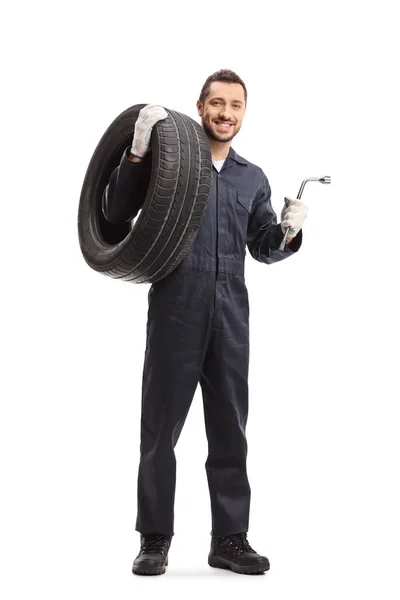 Auto mechanic holding a tire and a wrench — Stock Photo, Image