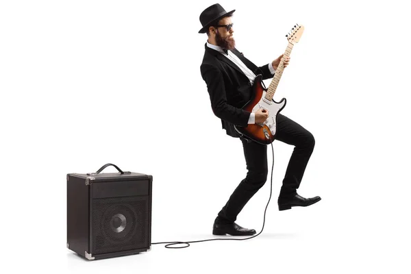 Bearded male artist in a suit playing a plugged electric guitar — Stock Photo, Image