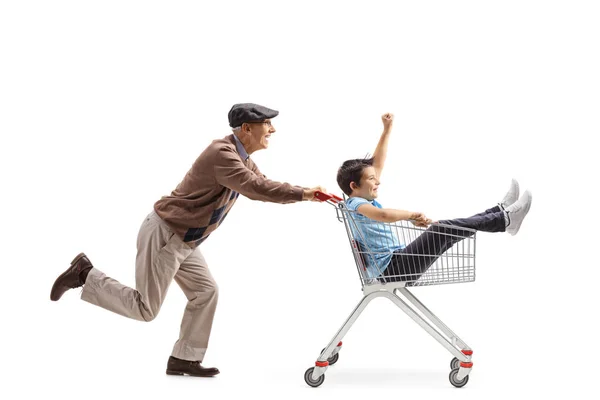 Großvater schiebt einen Einkaufswagen mit einem Jungen drinnen — Stockfoto