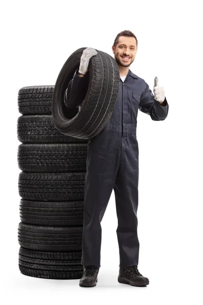 Auto mechanic holding a tire and showing thumbs up — Stock Photo, Image