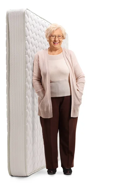 Elderly woman leaning on a bed mattres — Stock Photo, Image