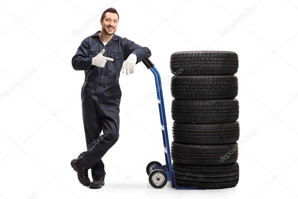 Auto mechanic pointing to a hand truck with car tires 