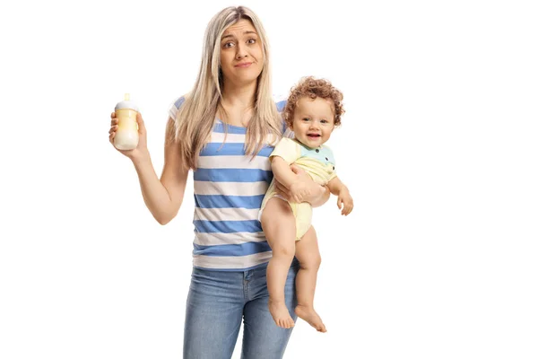 Jovem mãe cansada segurando um bebê e uma mamadeira de leite — Fotografia de Stock