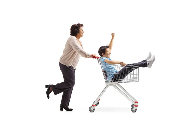 Babička tlačí svého vnuka v nákupním košíku — Stock fotografie