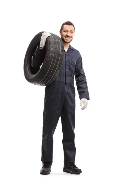 Mecânico carregando um pneu de carro e sorrindo para a câmera — Fotografia de Stock