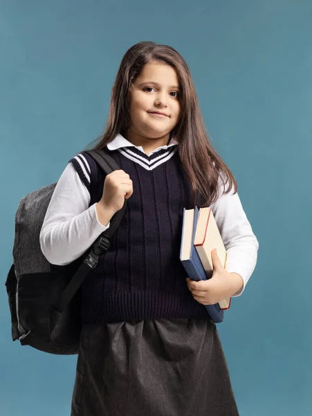 Школярка в уніформі тримає книги — стокове фото