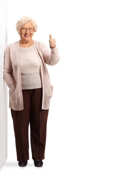 Anziani signora appoggiata alla parete e gesticolando pollice su segno — Foto Stock