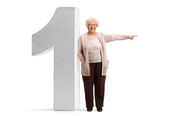 Donna anziana appoggiata su un enorme numero uno e che punta al si — Foto Stock