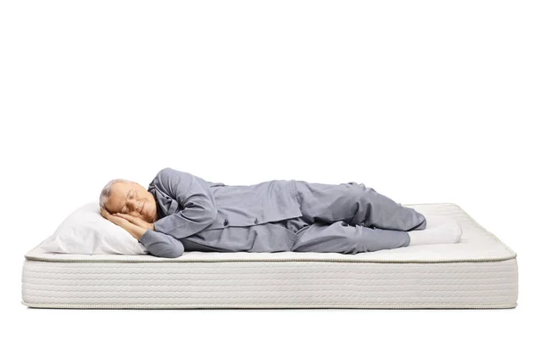 Älterer Mann schläft im Schlafanzug auf einer Matratze — Stockfoto