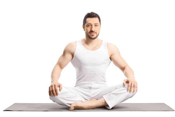 Young fit man sitting on a yoga mat — 스톡 사진