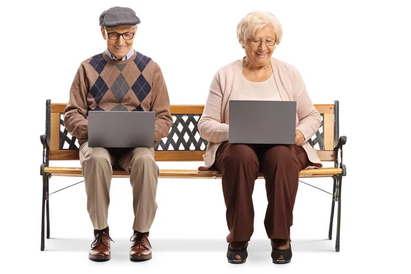 Пожилые мужчины и женщины на скамейке с ноутбуками — стоковое фото