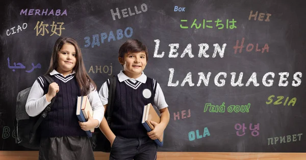 Children in school uniforms in front of a blackboard with text l — Stock Photo, Image