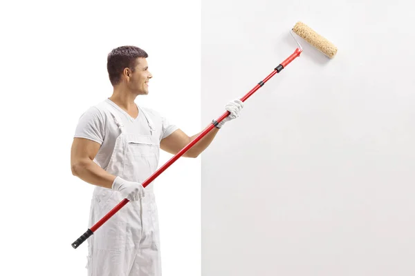 Pintor masculino pintando uma parede com um rolo — Fotografia de Stock