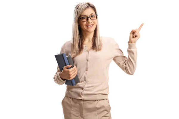 Young female teacher holding books and pointing — Stock Photo, Image