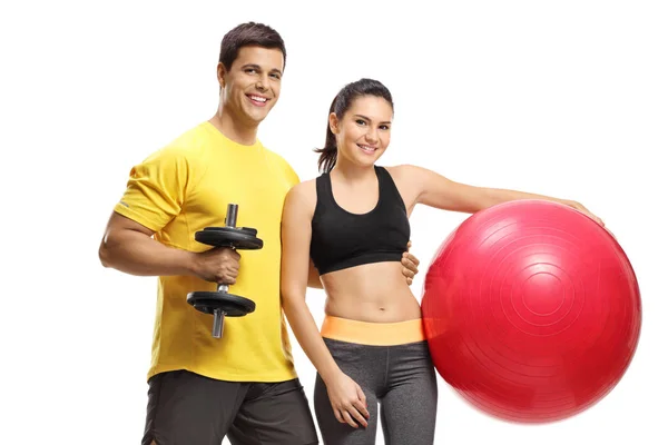 Jovem macho e fêmea com um halteres e pilates bola — Fotografia de Stock