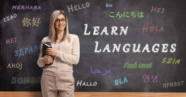 Young female language teacher standing in front of a blackboard — Stock Photo, Image