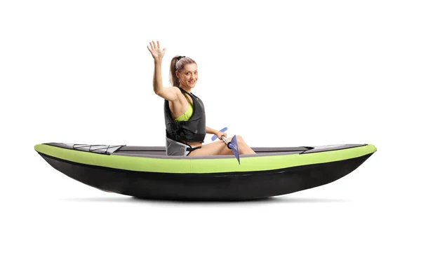 Young woman with a safety vest sitting inside a canoe and waving — Stock Photo, Image