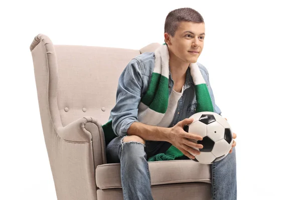 Mann mit Fußball und Schal sitzt im Sessel — Stockfoto