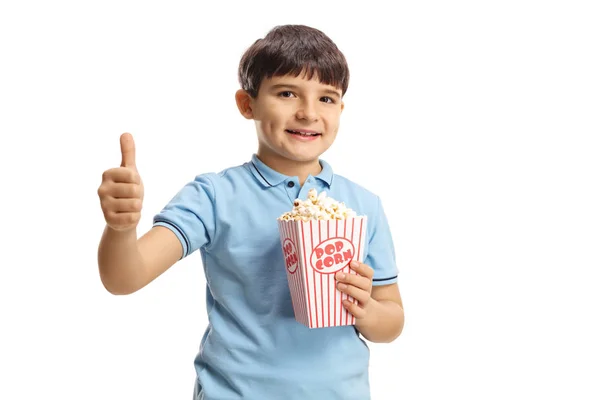 Sonriente niño sosteniendo una caja de palomitas de maíz y mostrando el pulgar hacia arriba —  Fotos de Stock