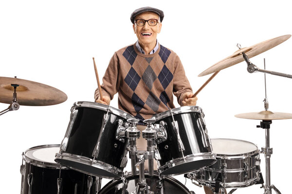 Senior drummer with a drum set smiling at the camera and playing