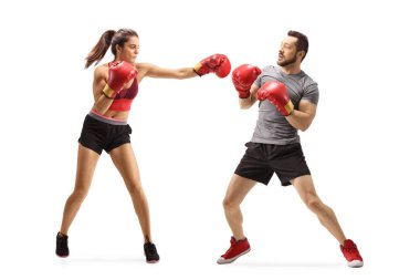 Genç bir kadın boks eldivenleriyle bir adamı yumrukluyor.