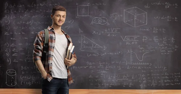 Estudiante masculino posando frente a una pizarra con fórmulas matemáticas —  Fotos de Stock