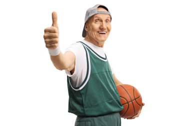 Elinde basketbol topuyla yaşlı bir adam baş parmağını kaldırıyor ve gülümsüyor. 