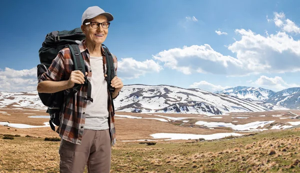 Elderly male hiker with a backpack climbing on a mountain — Stock Photo, Image